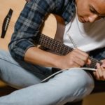 Musician songwriting on guitar or another instrument to overcome songwriter's block