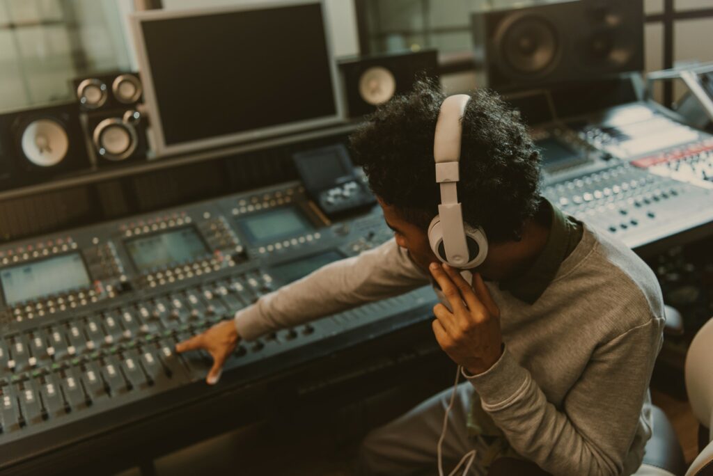 Musician with headphones at mixing board for the article: Top 13 Music Engineering Tips For Home Studio Recording