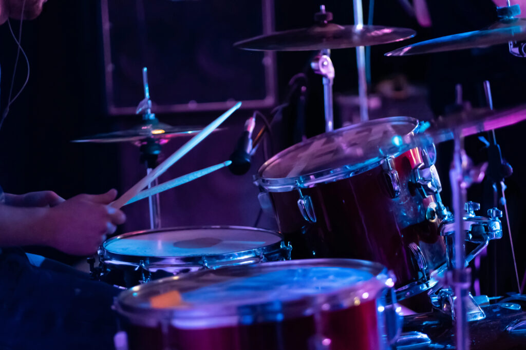 A musician who is a member of SoundExchange is drumming on stage at a concert.