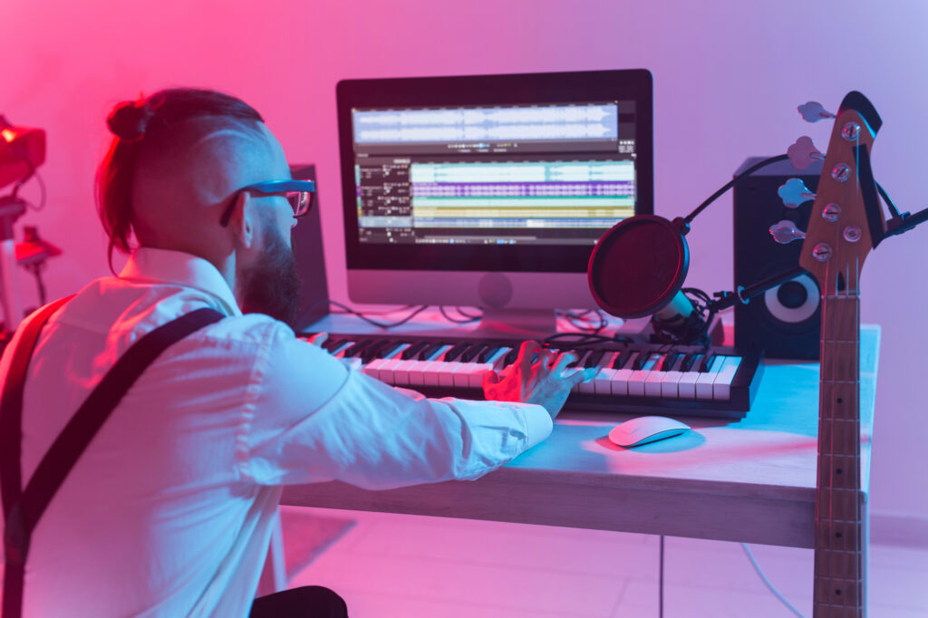 Hip musician creating music on keyboard with help of AI in a home studio.