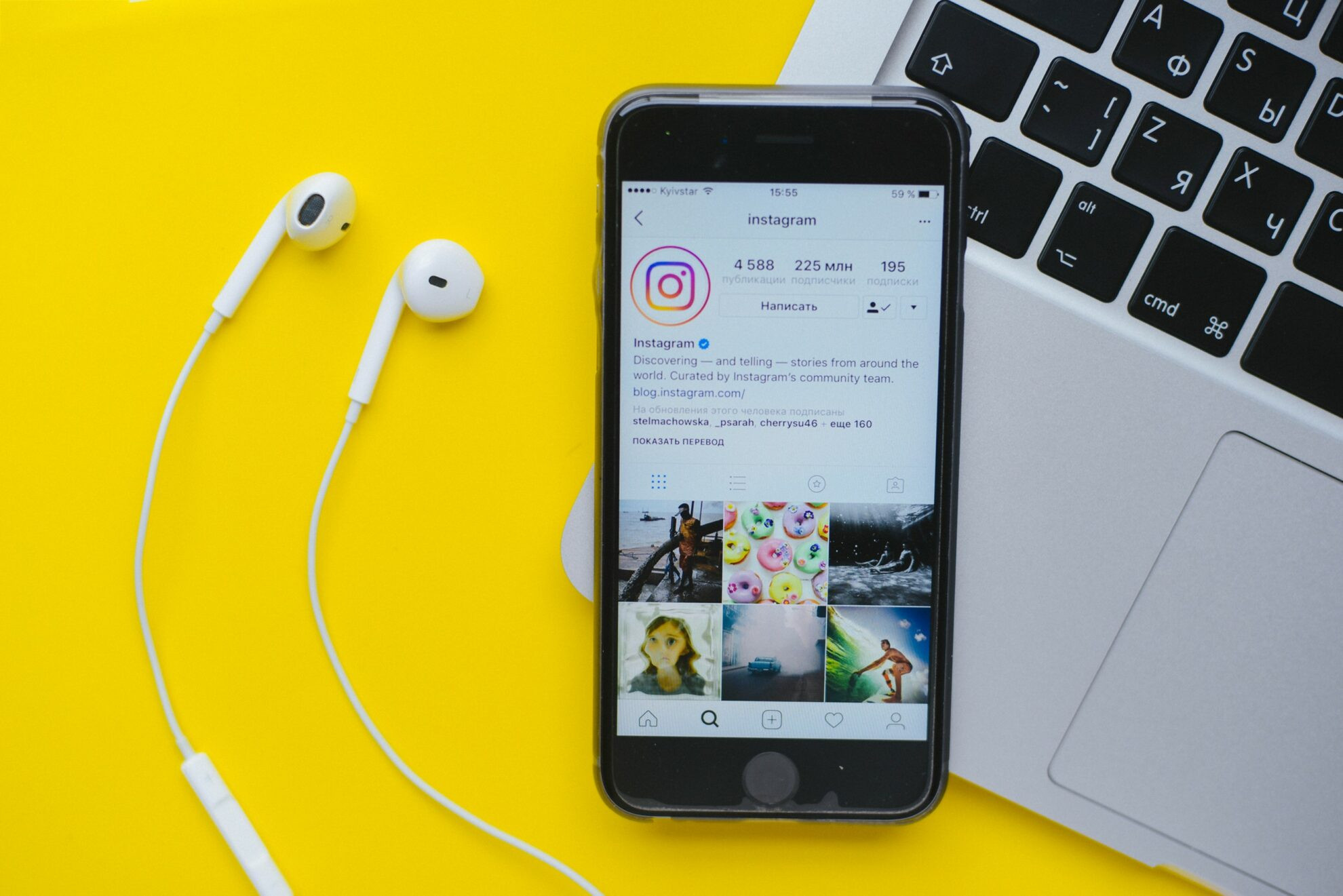 Mobile phone on a laptop with earphones open on an Instagram profile