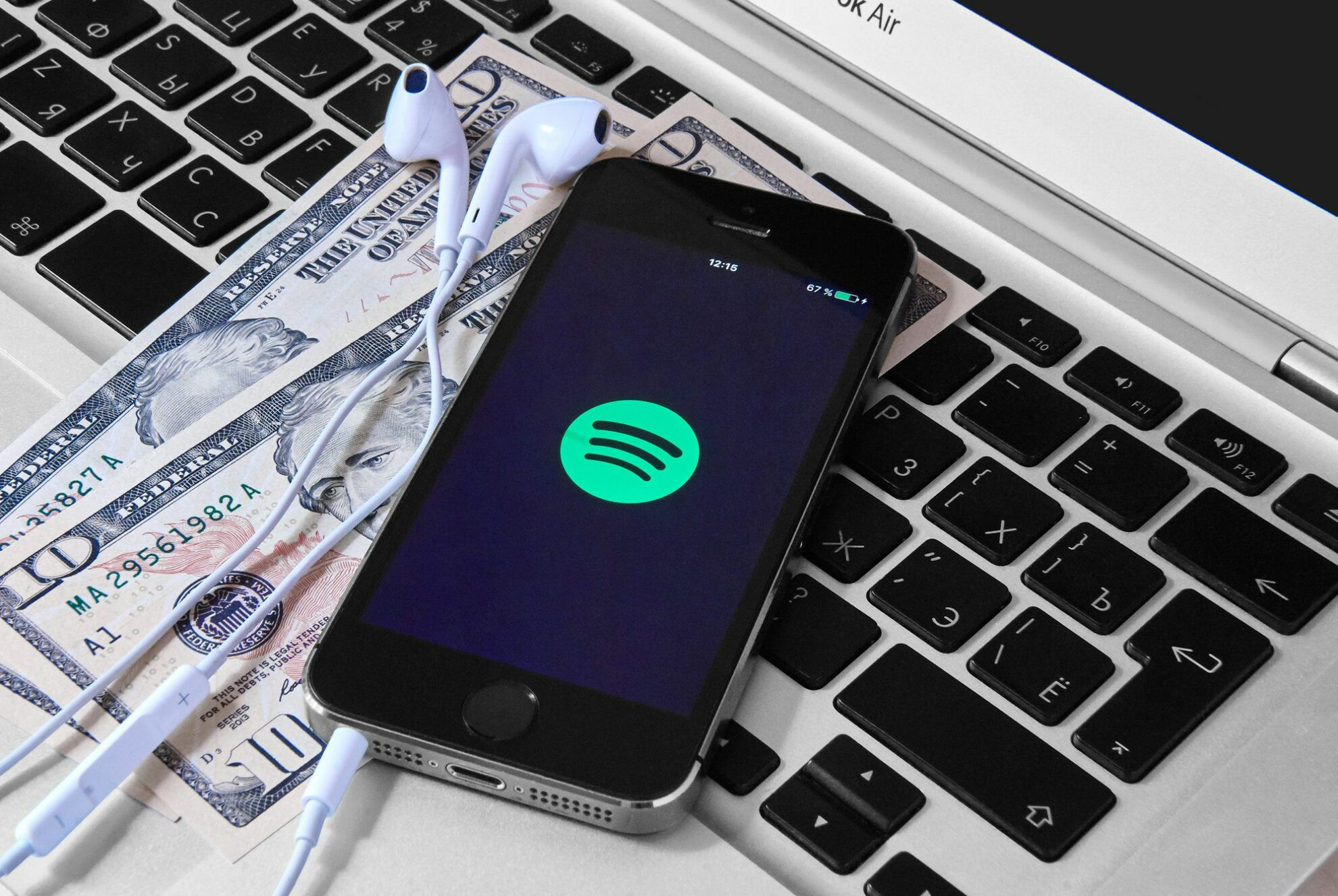 Mobile device displaying the Spotify logo on a laptop with money